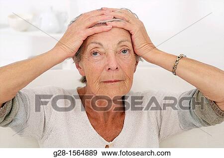 Stock Photo - ALZHEIMER, senior woman holding her forehead and trying to remember her souvenirs, or suffering from a headache. Fotosearch