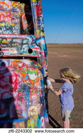 Amarillo Texas famous Cadillac Ranch child spraying paint off of Route 66 old Cadillacs buiried in ground on Rt 66 8. View Large Photo Image Stock Image - Amarillo Texas famous Cadillac Ranch child spraying paint off of Route 66 old Cadillacs buiried in ground on Rt 66 8.. Fotosearch