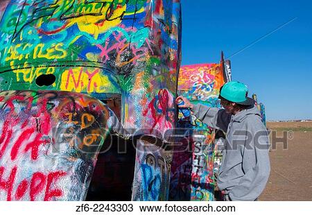 Amarillo Texas famous Cadillac Ranch teen spraying paint off of Route 66 old Cadillacs buiried in ground on Rt 66 9. View Large Photo Image Stock Image - Amarillo Texas famous Cadillac Ranch teen spraying paint off of Route 66 old Cadillacs buiried in ground on Rt 66 9.. Fotosearch