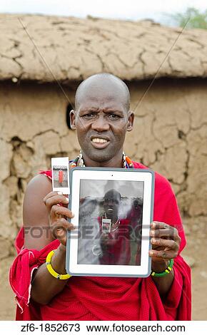 Stock Image - Amboseli National Park Kenya Africa safari Masai men showing photo on Digital Tablet in village Amboseli Maasai, beads, red, color, fun, 1. Fotosearch