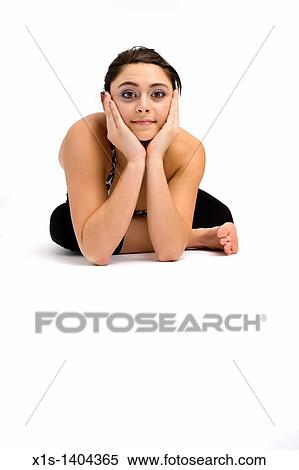 Stock Photography - American girl posing from a floor position, with her hands framing her face and her chin resting on the palms of her hands as she looks at the viewer.. Fotosearch