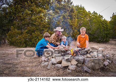 American man with his three boys having a good outdoor adventure time when they are roasting sausages over a camp fire. View Large Photo Image Stock Image - American man with his three boys having a good outdoor adventure time when they are roasting sausages over a camp fire.. Fotosearch