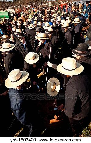 Stock Image - Amish men bid on farm equipment during the Annual Mud Sale to support the Fire Department in Gordonville, PA. Fotosearch