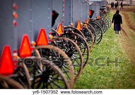 Stock Image - Amish women inspects horse buggies ready for auction during the Annual Mud Sale to support the Fire Department in Gordonville, PA. Fotosearch