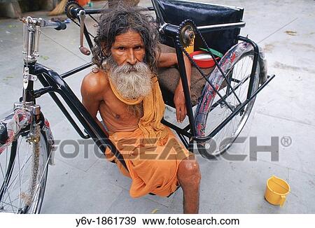 Stock Photo - Amputee with a wheelchair donated by an NGO. Jaipur, India. The NGO is Bhagwan Mahaveer Viklang Sahayata Samiti BMVSS, an organization that helps leg and feet amputees by giving them prosthesis, wheelchairs and even training some of them.. Fotosearch