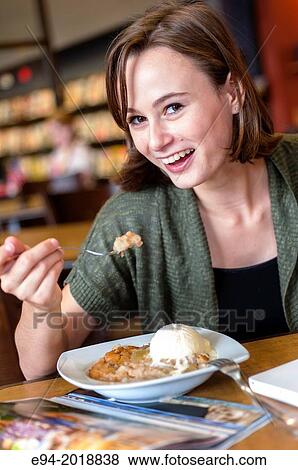 An 18 year old girl in a library eating a dessert. View Large Photo Image Stock Photo - An 18 year old girl in a library eating a dessert.. Fotosearch