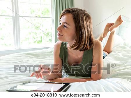 An 18 year old girl lying on her bed reading from a pad computer,. View Large Photo Image Stock Image - An 18 year old girl lying on her bed reading from a pad computer,.. Fotosearch