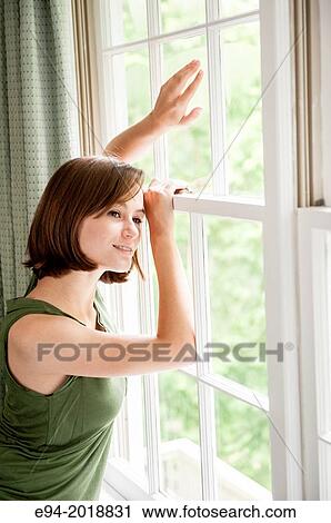 An 18 year old girl standing by a window in a house looking outside. View Large Photo Image Stock Image - An 18 year old girl standing by a window in a house looking outside.. Fotosearch