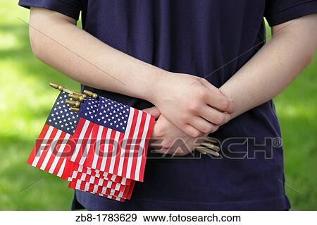 Stock Photo - An adolescent male holds miniature American flags in his hand at a Memorial Day ceremony in Raleigh, North Carolina, USA. Fotosearch