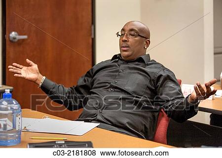 Stock Photo - An African American man expresses pleasure during a motivational lecture at a "Men's Career Workshop" on new business attire from Working Wardrobes. Fotosearch