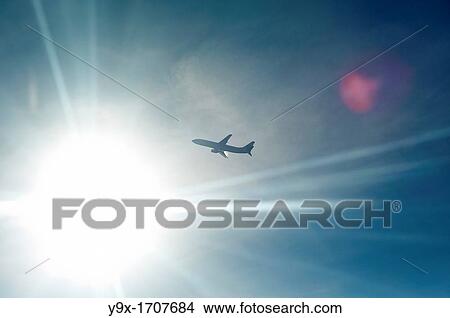 Picture - An airplane backlit by the sun in midair. Fotosearch