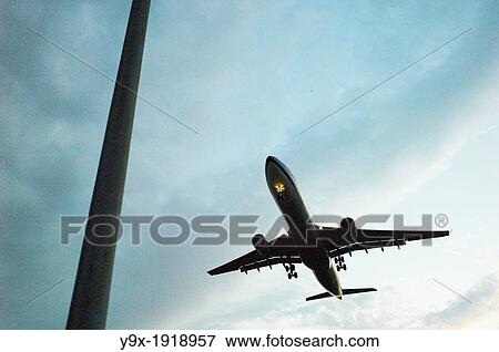 An airplane flies overhead at dusk View Large Photo Image Stock Photo - An airplane flies overhead at dusk. Fotosearch