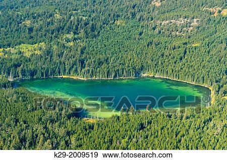 Stock Photo - An alpine lake surrounded by coniferous forest, Vancouver to Chilko Lake, British Columbia, Canada.. Fotosearch