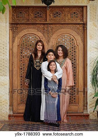 Stock Image - An Arab Muslim Malaysian family standing in front of an intricately designed doorway. Fotosearch