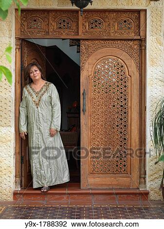 Stock Image - An Arab Muslim Malaysian woman standing in front of an intricately designed doorway. Fotosearch