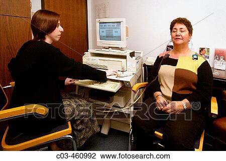Stock Image - An audiologist administers an auditory-nerve test to a middle-aged patient at a speech and hearing clinic in Orange, California. Fotosearch