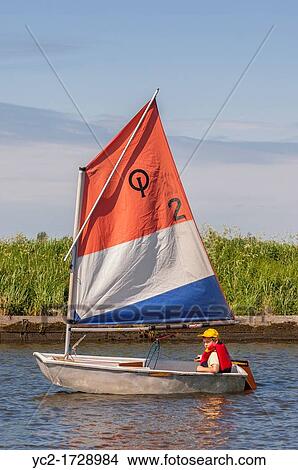 An eight year old boy sailing in an optimist dinghy boat in the Uk View Large Photo Image Picture - An eight year old boy sailing in an optimist dinghy boat in the Uk. Fotosearch