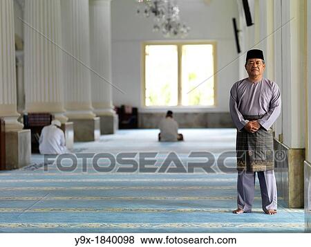 An elder man dressed in Muslim attire standing in the hallway of a Mosque View Large Photo Image Stock Photo - An elder man dressed in Muslim attire standing in the hallway of a Mosque. Fotosearch