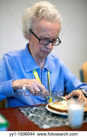 An elderly resident of a nursing home having breakfast at the communal breakfast table. View Large Photo Image Picture - An elderly resident of a nursing home having breakfast at the communal breakfast table.. Fotosearch