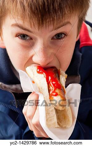 An eleven year old boy eating a hot dog with tomato ketchup sauce in the Uk View Large Photo Image Stock Photograph - An eleven year old boy eating a hot dog with tomato ketchup sauce in the Uk. Fotosearch