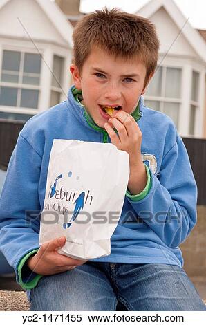 An eleven year old boy eats fish & chips on the sea wall in Aldeburgh, Suffolk, England, Britain, Uk View Large Photo Image Stock Photography - An eleven year old boy eats fish & chips on the sea wall in Aldeburgh, Suffolk, England, Britain, Uk. Fotosearch