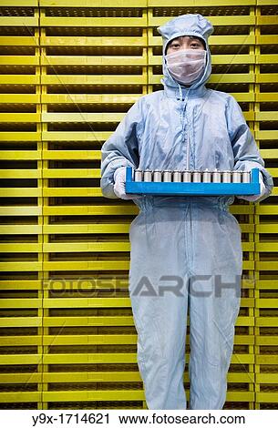 An employee of a battery company wearing a anti-contamination suit holding a crate of battery cells in front of a wall of crates. Shot in a Li-ion Battery Co which develops, manufactures, and markets cylindrical type rechargeable Li-ion batteries View Large Photo Image Stock Image - An employee of a battery company wearing a anti-contamination suit holding a crate of battery cells in front of a wall of crates. Shot in a Li-ion Battery Co which develops, manufactures, and markets cylindrical type rechargeable Li-ion batteries. Fotosearch