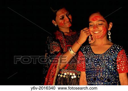 An indian woman is tying an earring to a girl during the hindu festival of Holi. India. View Large Photo Image Stock Image - An indian woman is tying an earring to a girl during the hindu festival of Holi. India.. Fotosearch