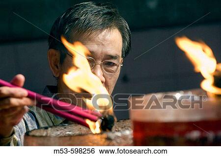 an indonesian man light up incense sticks in Vihara Dharma Bhakti temple in chinatown. west jakarta. indonesia. asia. View Large Photo Image Stock Photograph - an indonesian man light up incense sticks in Vihara Dharma Bhakti temple in chinatown. west jakarta. indonesia. asia.. Fotosearch