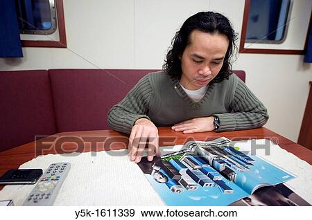 An Indonesian Seaman or sailor, reading a magazine in the galley on the container-vessel MV Flintercape, during a journey from Rotterdam, Netherlands, to Sundsvall, Sweden. The man is an? Able Seaman?, who generally works on deck. View Large Photo Image Stock Photo - An Indonesian Seaman or sailor, reading a magazine in the galley on the container-vessel MV Flintercape, during a journey from Rotterdam, Netherlands, to Sundsvall, Sweden. The man is an? Able Seaman?, who generally works on deck.. Fotosearch