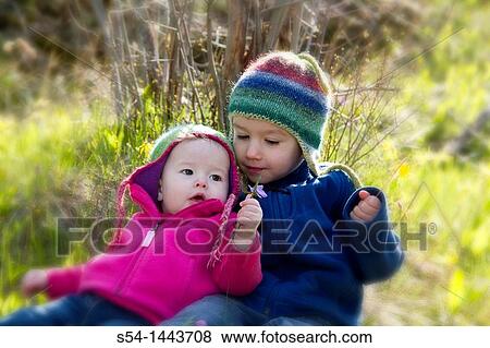 Stock Photo - An infant girl and toddler boy outdoors. Fotosearch