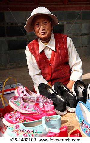 An old lady selling traditional style hand made embroidered shoes on old town street, Town of Guandu, Kunming, China View Large Photo Image Stock Photo - An old lady selling traditional style hand made embroidered shoes on old town street, Town of Guandu, Kunming, China. Fotosearch