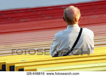 Stock Photograph - An old man at stadium bench. Fotosearch