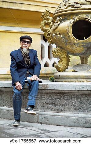An old man in a blue suit, wearing an artist hat and sunglasses at a temple in Vietnam View Large Photo Image Stock Photo - An old man in a blue suit, wearing an artist hat and sunglasses at a temple in Vietnam. Fotosearch