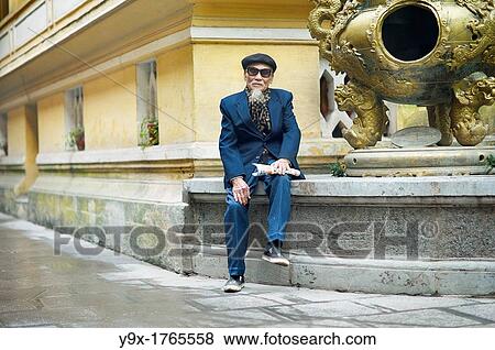 An old man in a blue suit, wearing an artist hat and sunglasses at a temple in Vietnam View Large Photo Image Stock Photo - An old man in a blue suit, wearing an artist hat and sunglasses at a temple in Vietnam. Fotosearch