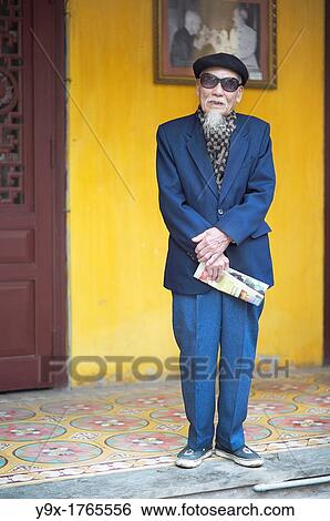 An old man in a blue suit, wearing an artist hat and sunglasses at a temple in Vietnam View Large Photo Image Stock Photograph - An old man in a blue suit, wearing an artist hat and sunglasses at a temple in Vietnam. Fotosearch
