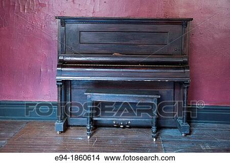 An old upright piano against a red wall. View Large Photo Image Picture - An old upright piano against a red wall.. Fotosearch