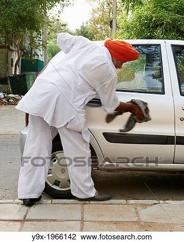 An older man wearing a bright orange turban wipes his compact car down in Delhi. View Large Photo Image Stock Image - An older man wearing a bright orange turban wipes his compact car down in Delhi.. Fotosearch