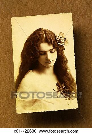 Stock Image - Antique picture of a long-haired young woman with a rose, 1920? s. Fotosearch