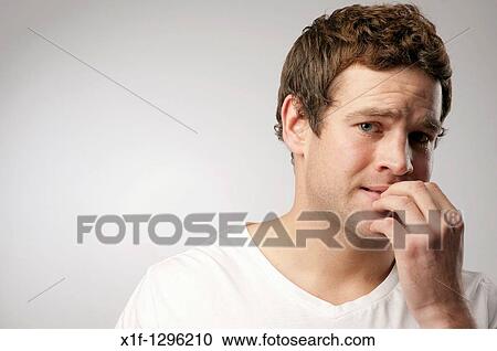 Stock Image - anxious nervous white caucasian male man biting his nails. Fotosearch