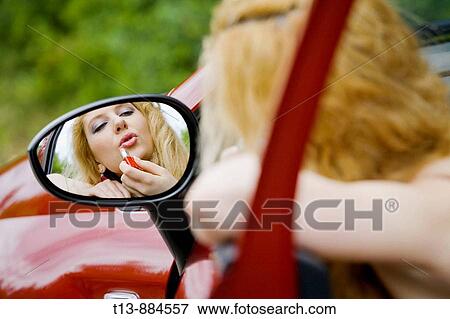 Stock Photo - Applying make-up in car's outside mirror. Fotosearch