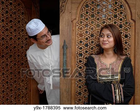 Stock Photography - Arab Muslim Malaysian father and daughter looking at each other in front of an intricately designed doorway. Fotosearch