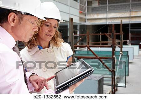 Stock Image - Architect and client with tablet PC in construction site. Fotosearch