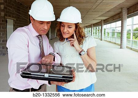 Stock Photograph - Architect and client with tablet PC in construction site. Fotosearch