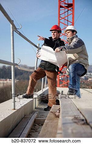 Architect and construction worker looking at blueprints, personal protective equipment, housing construction View Large Photo Image Stock Image - Architect and construction worker looking at blueprints, personal protective equipment, housing construction. Fotosearch