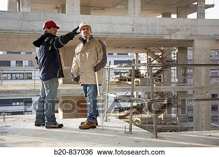Stock Photograph - Architect and construction worker, personal protective equipment, housing construction, concrete skeleton. Fotosearch