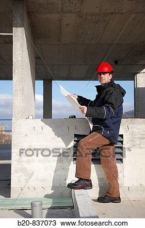 Architect looking at blueprints, personal protective equipment, housing construction View Large Photo Image Stock Image - Architect looking at blueprints, personal protective equipment, housing construction. Fotosearch