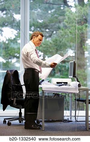 Stock Image - Architect with blueprints in office. Fotosearch