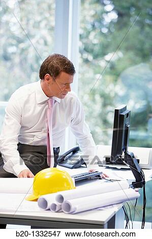 Stock Photo - Architect with blueprints in office. Fotosearch