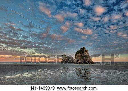 Archway Islands, sunrise lights up high clouds, Wharariki beach, near Collingwood, Golden Bay, New Zealand View Large Photo Image Stock Photo - Archway Islands, sunrise lights up high clouds, Wharariki beach, near Collingwood, Golden Bay, New Zealand. Fotosearch