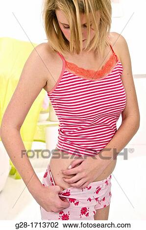 Stock Image - arms of young woman scratching her itching hip in red underwear, suffering from psoriasis or a rash. Fotosearch